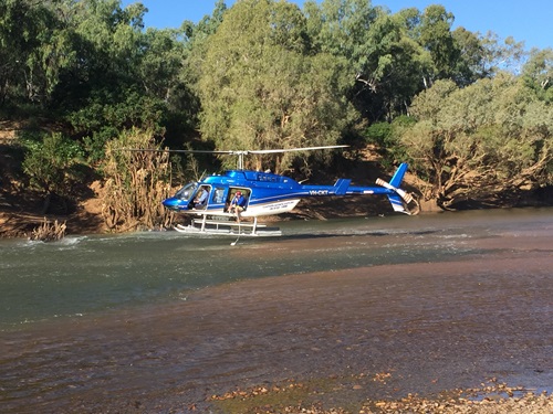 Helicopter hovering over water taking samples from the surface water of the Fitzroy River.