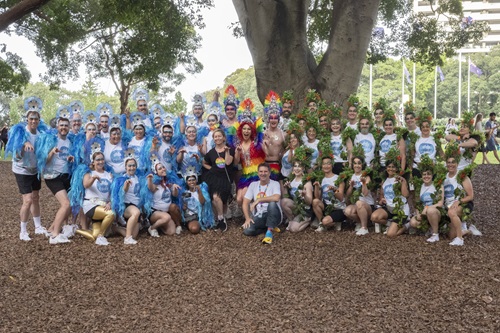 Group of people posing together for a photo in front of the trunk of a large tree.
