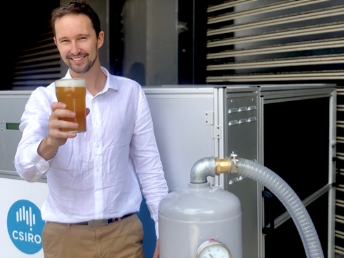 Scientist holds beer beside gas cylinder