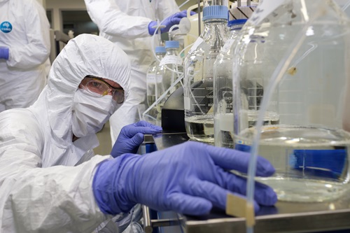 Scientist in protective clothing working in a lab.