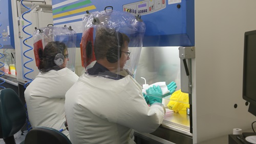 Two people working in a laboratory in protective suits. 