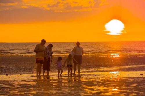 People standing on a beach at sunset. 