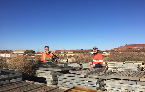 Two scientists stand beside piles of rock samples