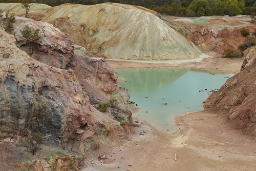 A discoloured pool of blue water surrounded by rocks