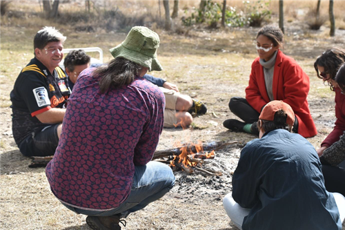 A group of people sitting around a campfire. 