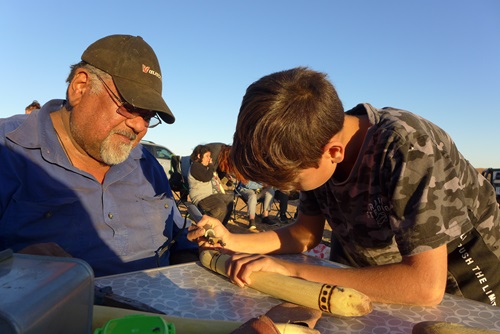 Person showing a boy boy how to decorate clap sticks.