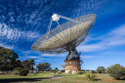 CSIRO Parkes Wiradjuri telescope during the day with blue sky and scattered clouds as the backdrop.