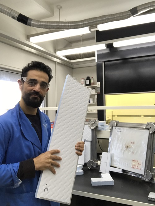 Scientist holds up a white panel. 