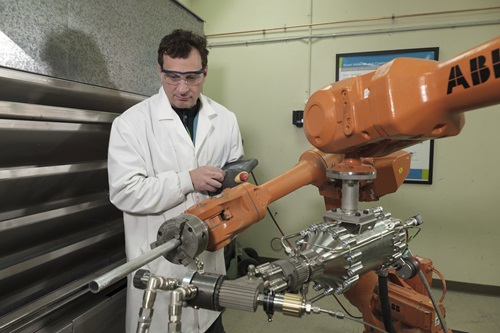 Person in a lab coat operating a cold spray machine.