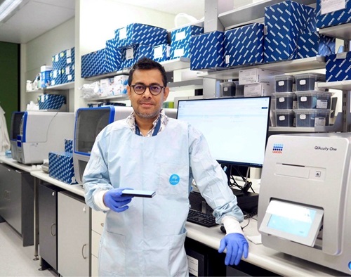Scientist standing next to digital PCR used to quantify SARS-CoV 2 RNA in sewage or other environmental samples.