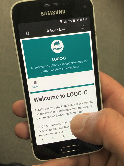 Hand holding a smart phone with CSIROs LOOC-C carbon farming app installed and showing open on the screen.