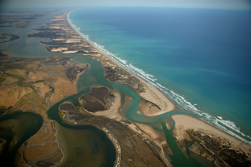 Aerial view of a long beach with lakes on one side and the ocean on the other and a river mouth entering the ocean