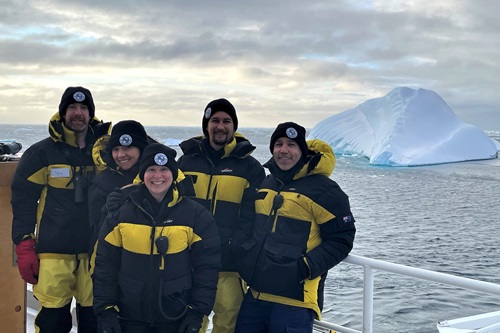 A photo of the TEMPO predator observation team standing in front of an iceberg