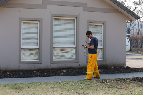 Researcher stands beside house holding measurement device