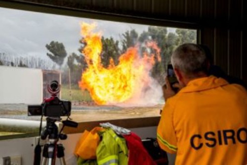 Scientist in high vis takes photos of a burning structure