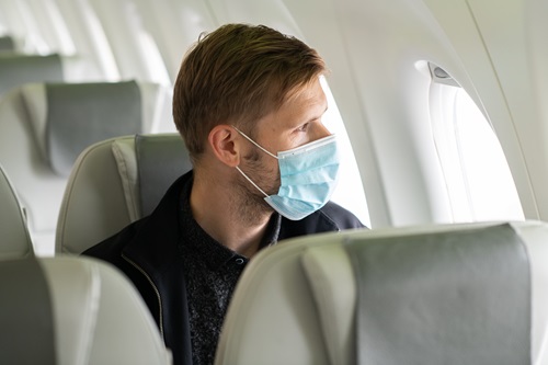Man with mask sits on a plane