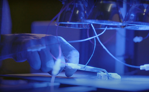 Gloved hand holding rock sample with  tweezers  under sensor equipment