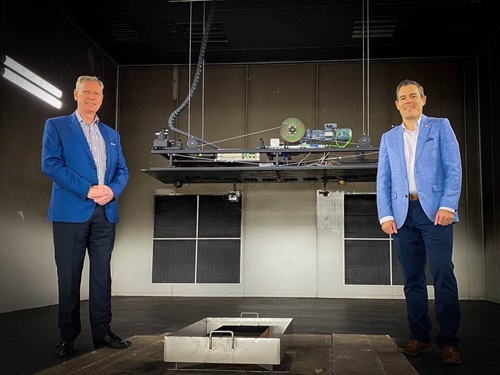 Two people posing inside a smoke alarm and smoke detector test facility.