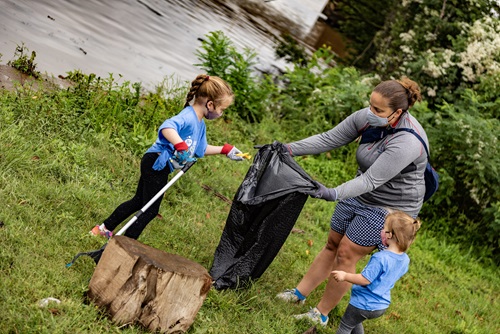 Women holding garbage bag with two children collecting rubbish