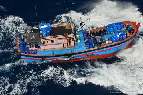 A blue and red fishing boat travelling in rough seas