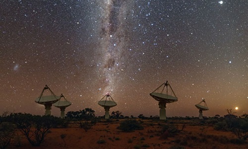 Six of the ASKAP telescopes at night with the Milky Way stretching vertically above. 