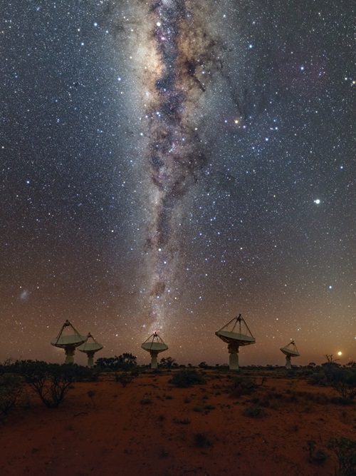 Six of the ASKAP telescopes at night with the Milky Way stretching vertically above. 