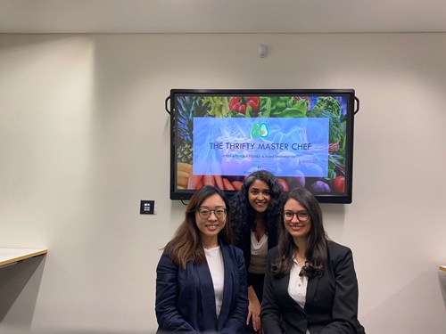 Three members of the Plasticombat team standing in front of a large screen.