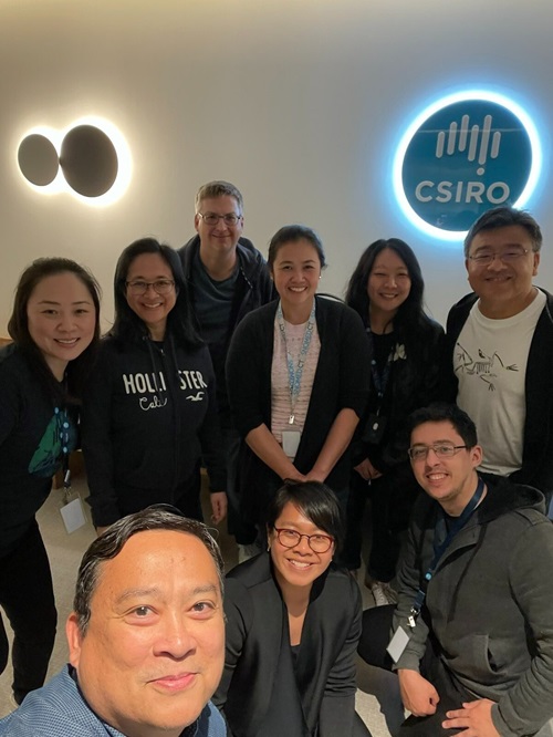 Group of people standing in a room with CSIRO image in the background