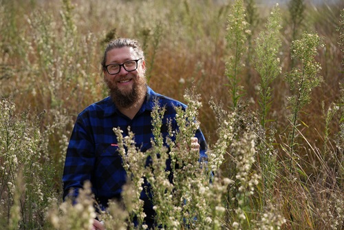 Dr Ben Gooden, CSIRO research scientist surrounded by fleabane weed
