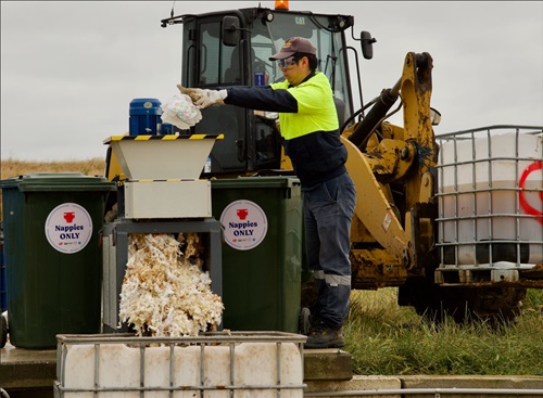 Worker puts nappy waste in a shredder