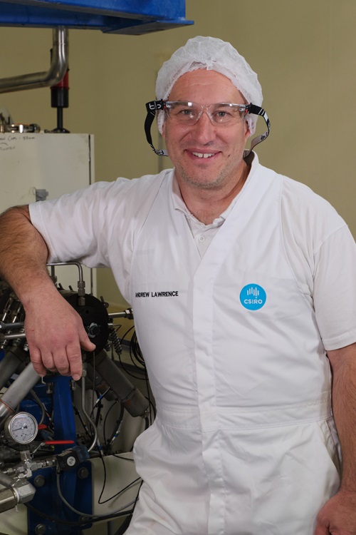 Image of a man involved in the creation of the Nutri V vegetable snack in white CSIRO working clothes and a hair net leaning on machinery.