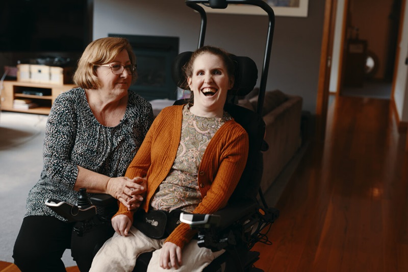 One person on a wheelchair with another person sitting beside her