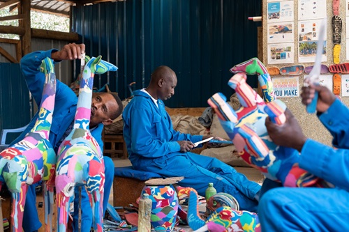 Workers wearing blue suits making animal artworks out of thongs