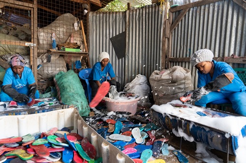 Workers wearing blue uniforms with piles of thong pollution