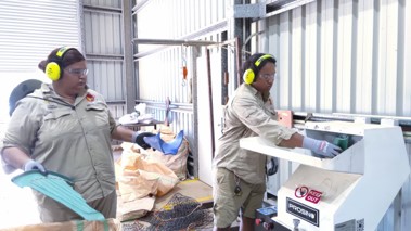 People wearing safety ear muffs using a shruder machine to process plastic waste