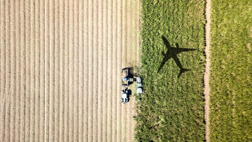 Image of a shadow of a plane flying over crops
