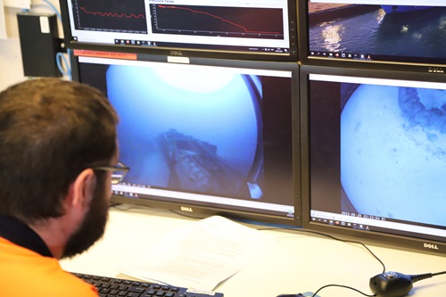 A person looking at two computer screens showing underwater vision.