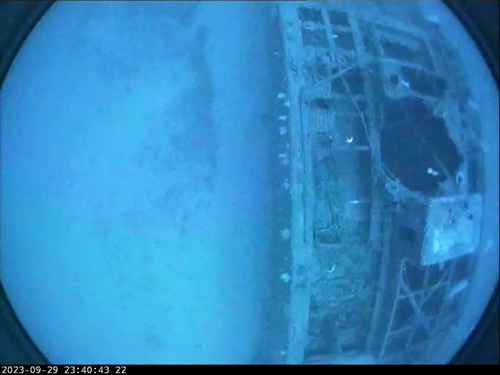 An underwater image showing a shipwreck on the seafloor.