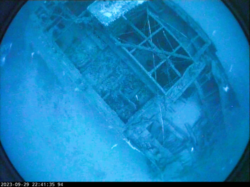 An underwater image showing a shipwreck on the seafloor.