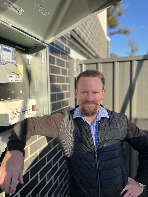 A man standing next to a meter box.