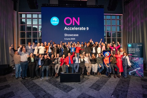 Three rows of people with hands in the air facing the camera in front of a banner with the words ON Accelerate Showcase June 2025.
