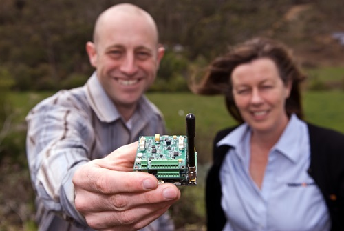 Two people facing the camera with one holding out a microchip towards the camera.