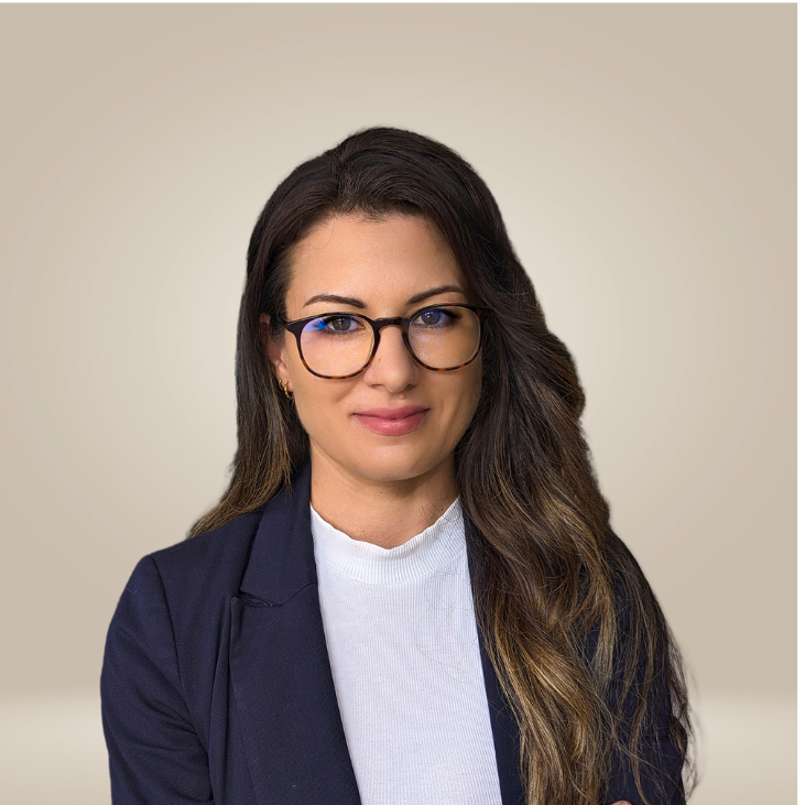 An upper body headshot of a female with long hair, black rimmed glasses, white shirt and black blazer.