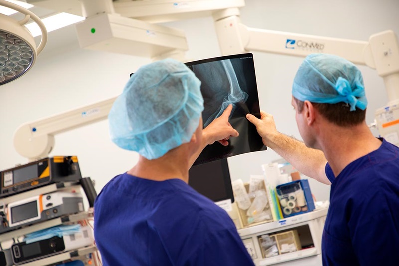 Surgeons looking at an x-ray image of a knee joint. 