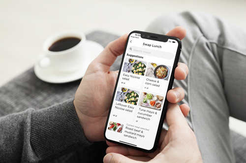 Person viewing the Total Wellbeing Diet on their phone while sitting down, visible is the meal swap options