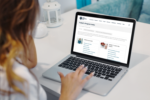 Woman viewing the Total Wellbeing Diet while using a laptop, viewing the program index page