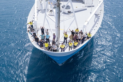 A group of people on the bow of a ship at sea seen from an elevated position.