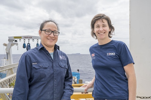 Two people standing on the deck of a ship at sea.