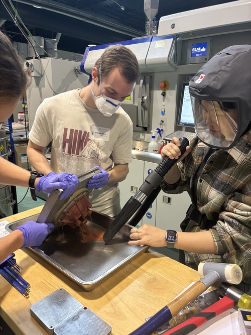 CSIRO’s Dr Cherry Chen (right) with University of Melbourne students depowdering the injector.