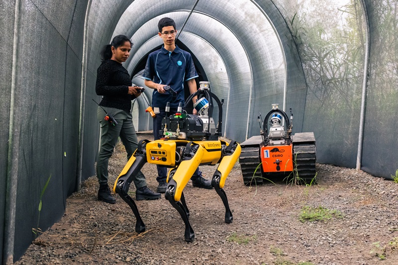 Two researchers standing alongside two robots.